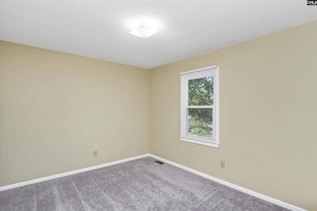carpeted empty room with a textured ceiling, baseboards, and visible vents