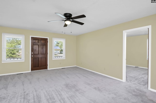 empty room with a healthy amount of sunlight, baseboards, a ceiling fan, and carpet flooring