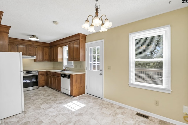 kitchen with an inviting chandelier, white appliances, light countertops, under cabinet range hood, and visible vents