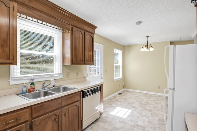 kitchen featuring a sink, a chandelier, white appliances, and a healthy amount of sunlight