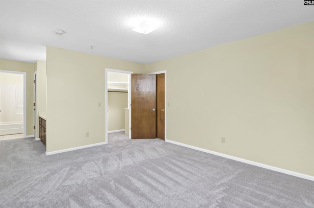 unfurnished bedroom with light colored carpet, baseboards, a spacious closet, and a closet