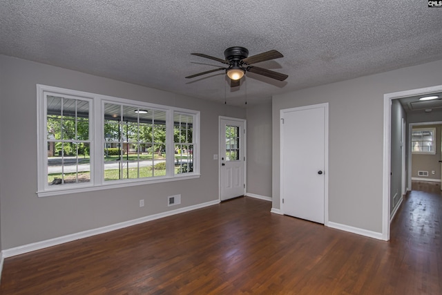 spare room featuring a healthy amount of sunlight, baseboards, a ceiling fan, and dark wood-type flooring