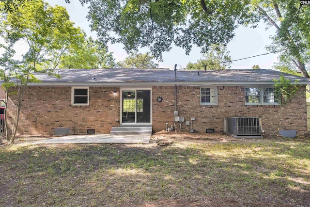 rear view of property featuring brick siding, crawl space, central air condition unit, a patio, and a lawn