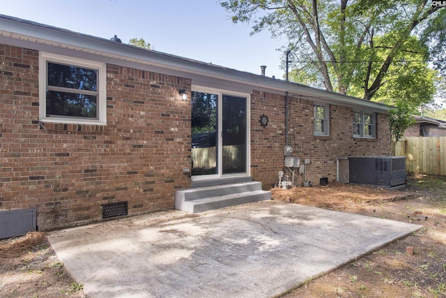 rear view of house with fence, brick siding, crawl space, entry steps, and a patio