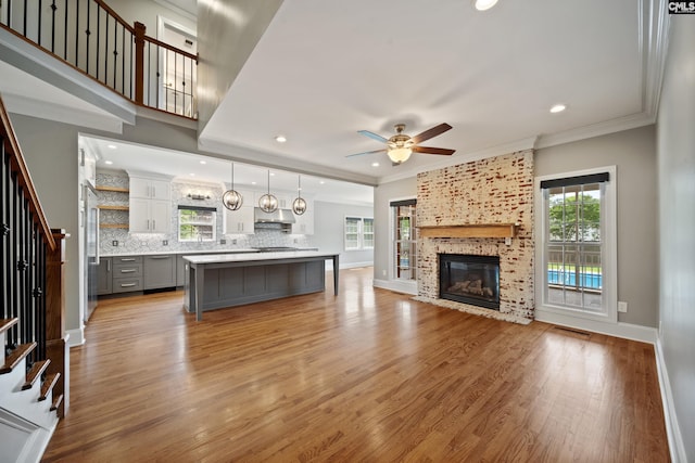 living room featuring stairs, a ceiling fan, plenty of natural light, and light wood-style floors