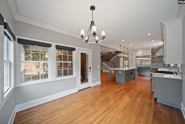 kitchen with crown molding, a chandelier, a kitchen island, visible vents, and stainless steel built in refrigerator