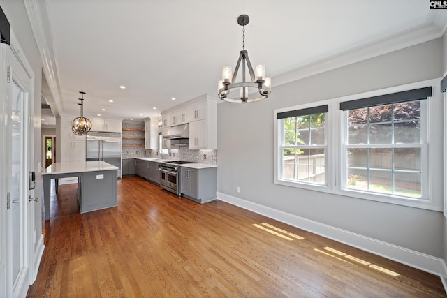 kitchen with crown molding, light countertops, a chandelier, baseboards, and premium appliances