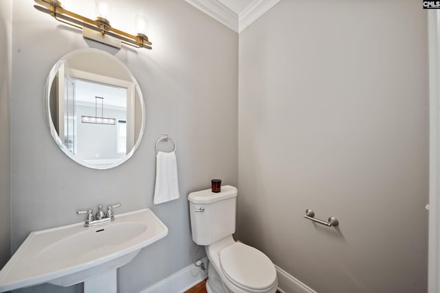 half bathroom featuring crown molding, baseboards, toilet, and a sink