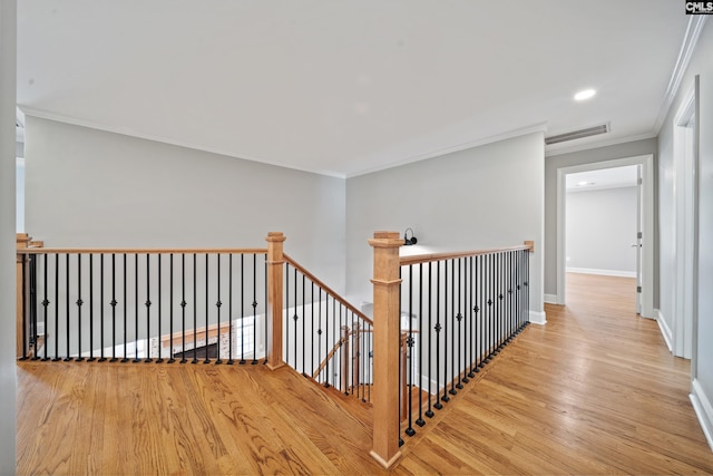 corridor with an upstairs landing, ornamental molding, wood finished floors, and visible vents