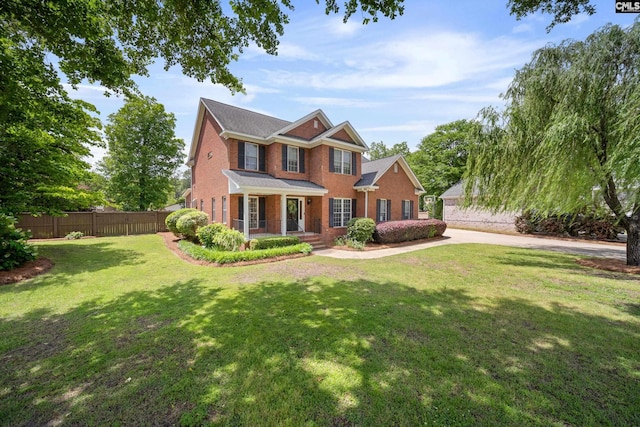 view of front of house featuring covered porch, brick siding, fence, and a front yard
