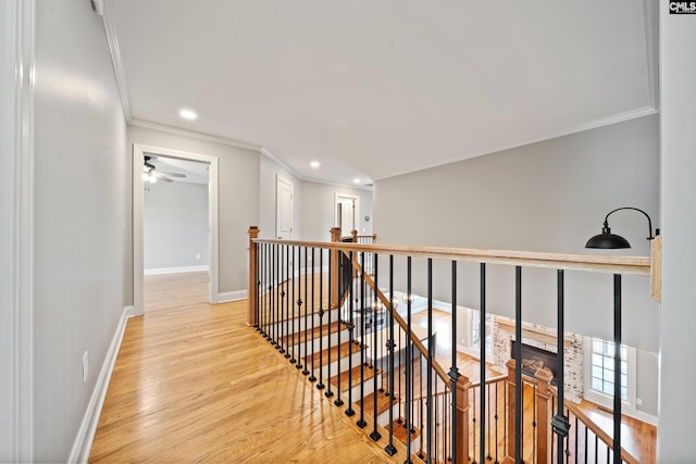 corridor featuring wood finished floors, baseboards, an upstairs landing, ornamental molding, and recessed lighting