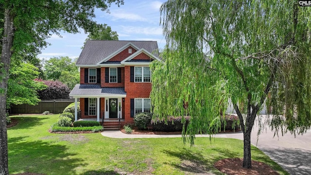 view of front of home with brick siding, fence, and a front yard