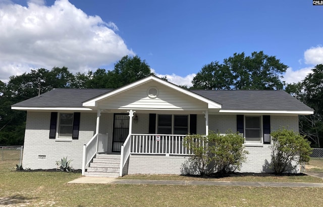 view of front of home featuring fence, covered porch, a front lawn, and brick siding