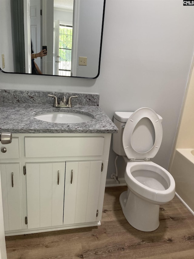 full bathroom featuring vanity, toilet, a tub, baseboards, and wood finished floors
