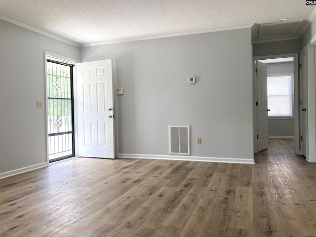 interior space featuring ornamental molding, wood finished floors, and visible vents