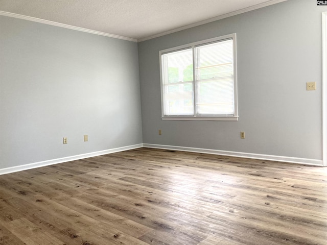 spare room with baseboards, ornamental molding, a textured ceiling, and wood finished floors