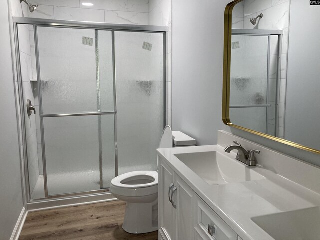 bathroom featuring toilet, a shower stall, wood finished floors, and vanity