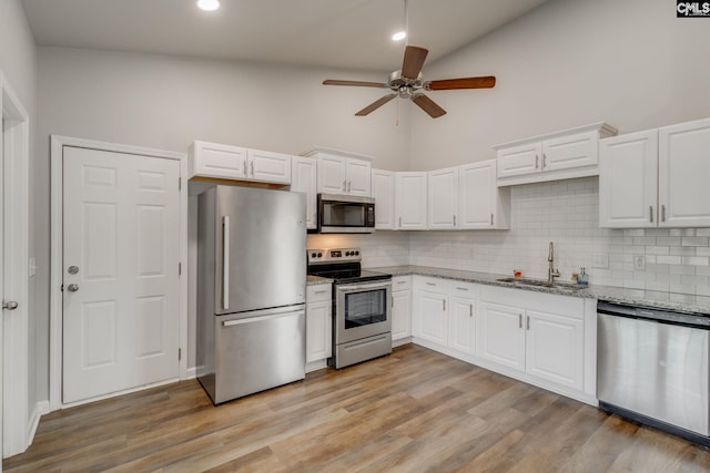 kitchen featuring decorative backsplash, a sink, white cabinets, a ceiling fan, and appliances with stainless steel finishes