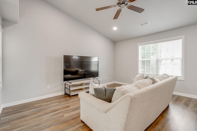 living room with ceiling fan, visible vents, wood finished floors, baseboards, and lofted ceiling