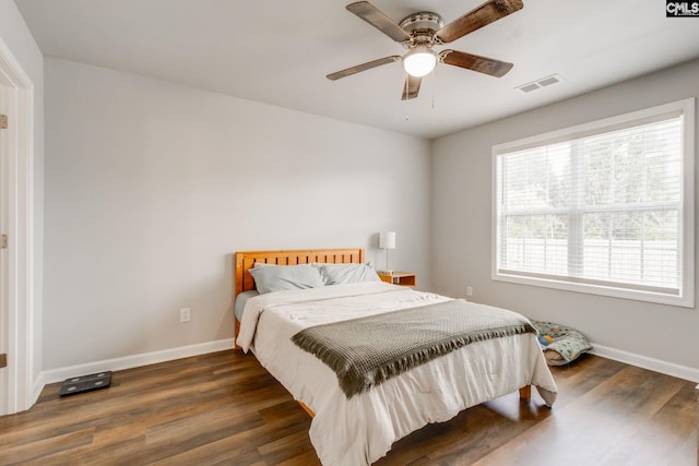 bedroom with visible vents, a ceiling fan, baseboards, and wood finished floors
