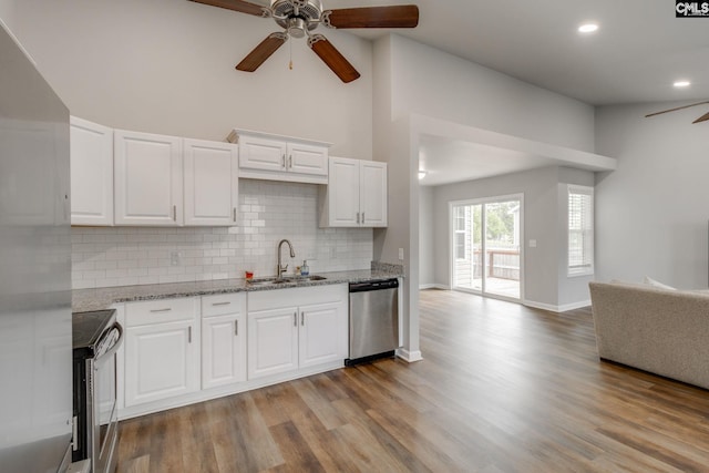 kitchen with a sink, a ceiling fan, open floor plan, stainless steel appliances, and tasteful backsplash