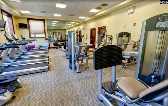 workout area featuring carpet flooring, arched walkways, and a paneled ceiling