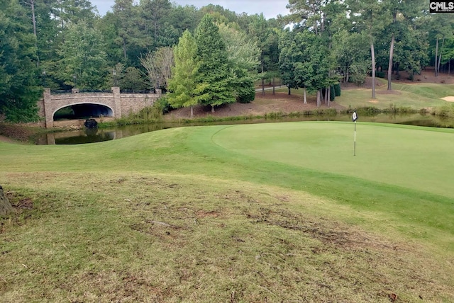 view of community featuring a lawn, a water view, and view of golf course