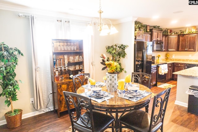 dining room with an inviting chandelier, baseboards, crown molding, and wood finished floors