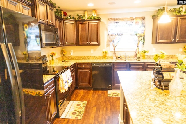 kitchen featuring crown molding, light stone countertops, a sink, dark wood-type flooring, and black appliances