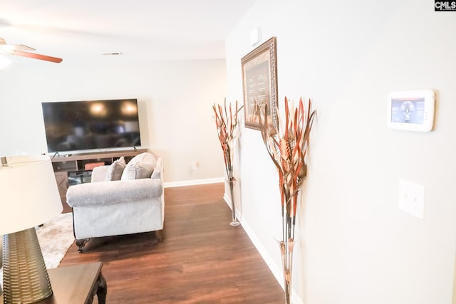 living room featuring baseboards, ceiling fan, visible vents, and wood finished floors