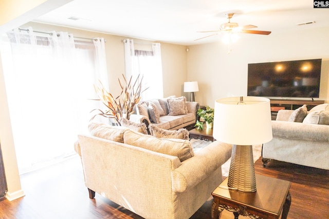 living area with visible vents, a ceiling fan, and wood finished floors