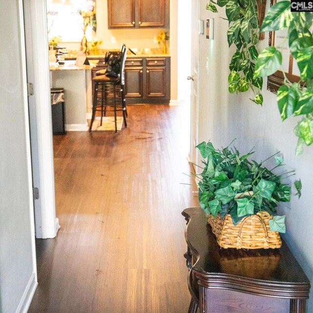 corridor featuring baseboards and wood finished floors