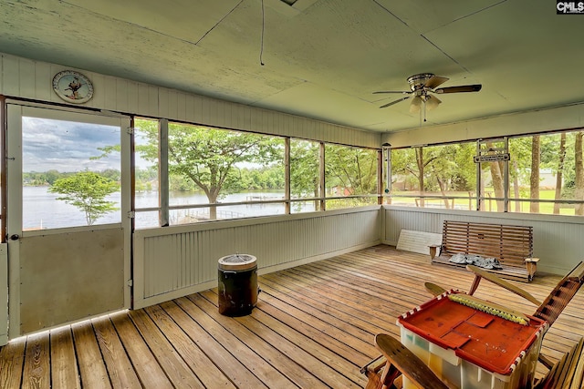 unfurnished sunroom featuring a ceiling fan, plenty of natural light, and a water view