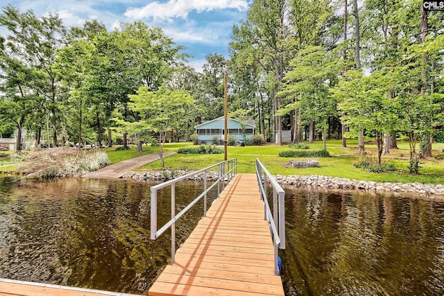 view of dock with a lawn and a water view