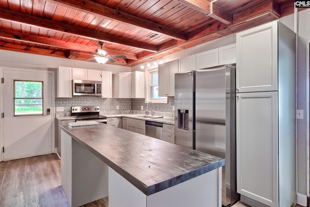 kitchen featuring light wood-type flooring, beam ceiling, a sink, wooden ceiling, and stainless steel appliances