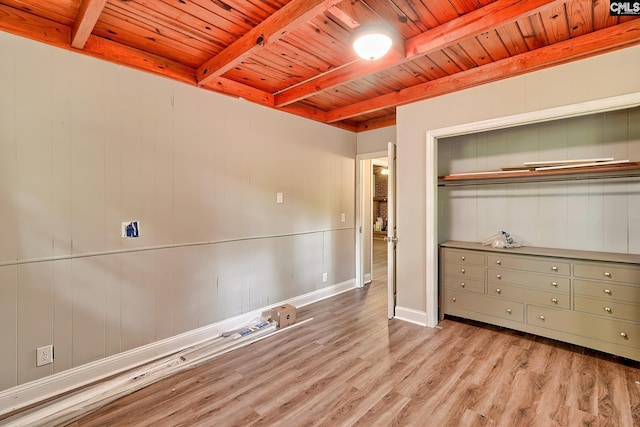 unfurnished bedroom featuring light wood-type flooring, wood ceiling, beam ceiling, and a closet