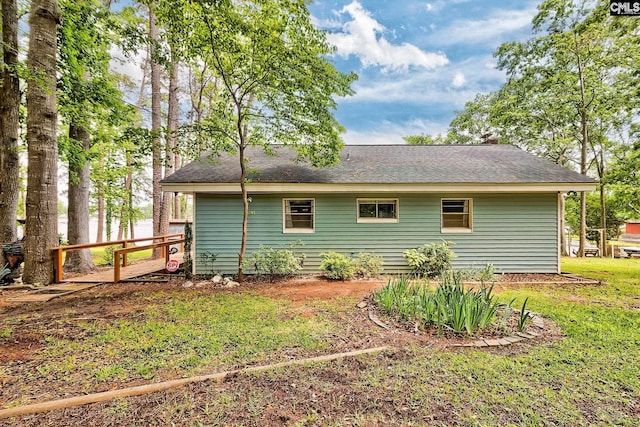 back of property with a yard and roof with shingles
