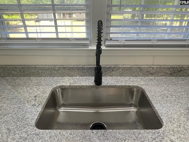 interior details with light stone counters and a sink