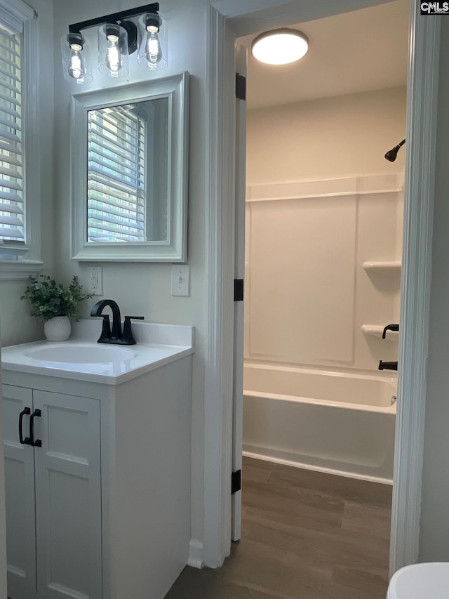 bathroom with shower / bathtub combination, wood finished floors, and vanity