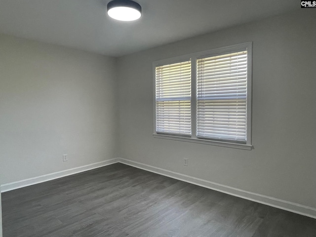spare room with baseboards, dark wood-type flooring, and plenty of natural light