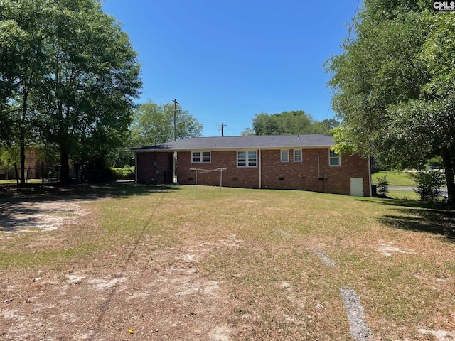 back of property featuring a yard, brick siding, and crawl space