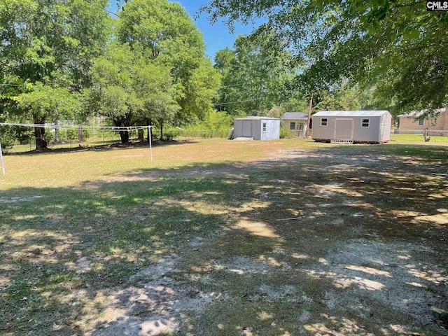 view of yard with a storage unit, fence, and an outbuilding