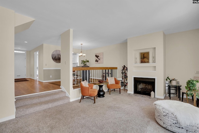 carpeted living area with baseboards, a fireplace with flush hearth, recessed lighting, and an inviting chandelier