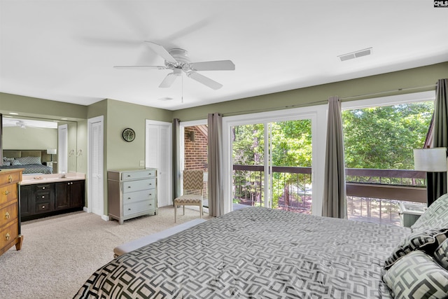bedroom with light colored carpet, ensuite bath, two closets, a ceiling fan, and visible vents