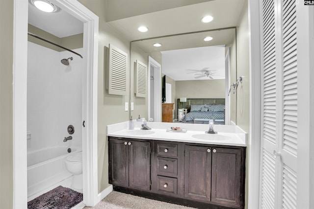 ensuite bathroom with double vanity, a ceiling fan, a sink, and a closet