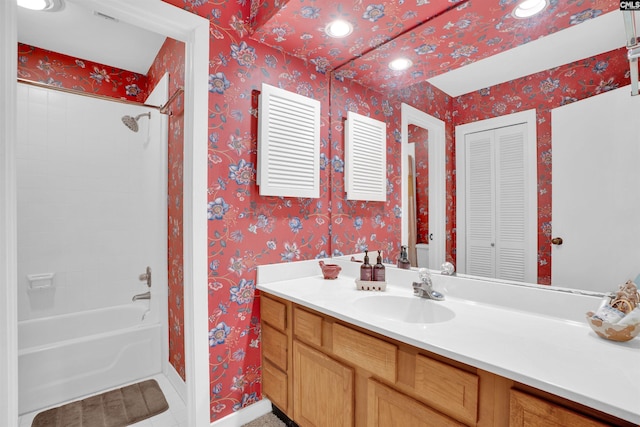 bathroom featuring vanity, baseboards, wallpapered walls, shower / bathing tub combination, and a closet