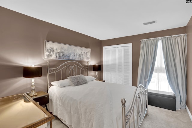 carpeted bedroom with visible vents and a closet