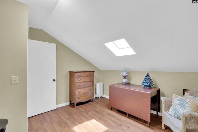 interior space with baseboards, lofted ceiling with skylight, wood finished floors, and radiator heating unit