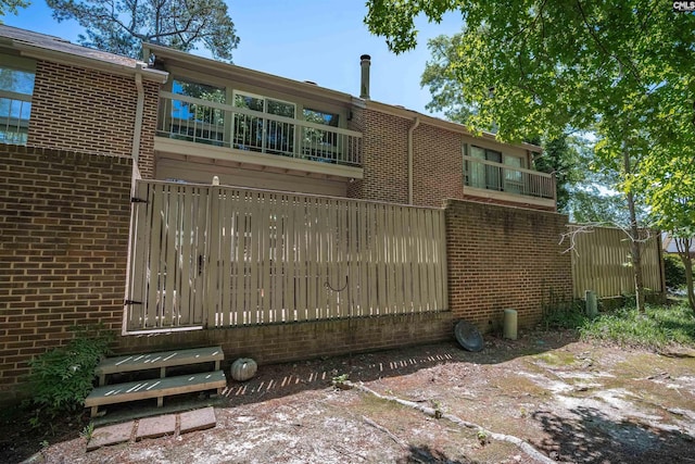 back of house featuring brick siding and fence