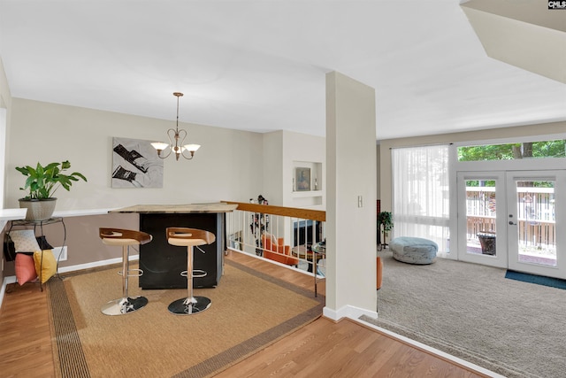 interior space with baseboards, french doors, a chandelier, and wood finished floors